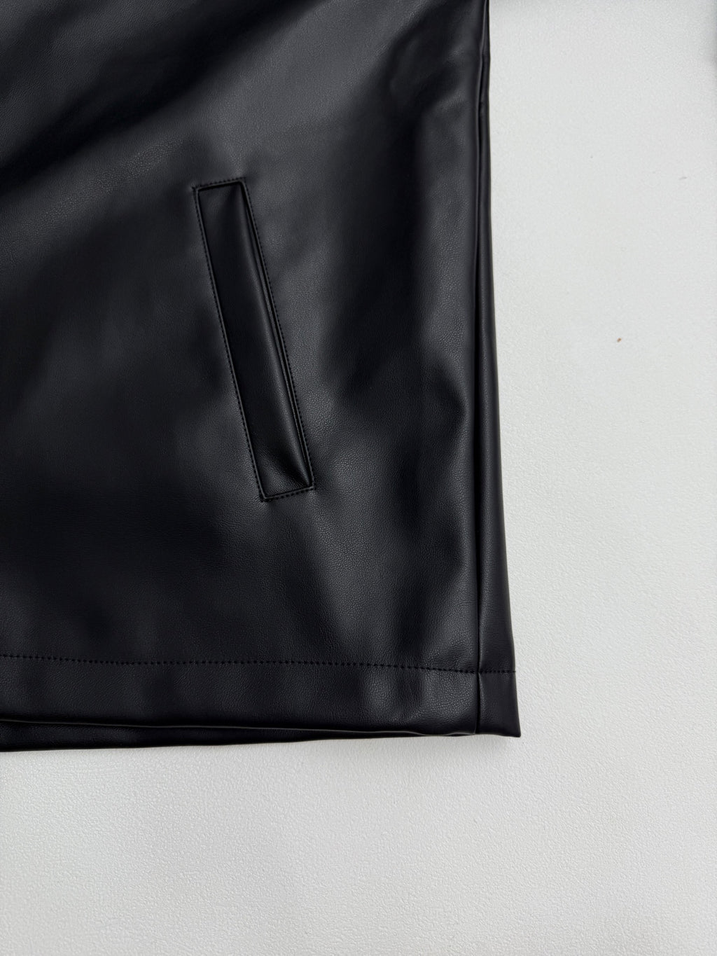 Black leather-look jacket sleeve cuff and side pocket with vertical stitch