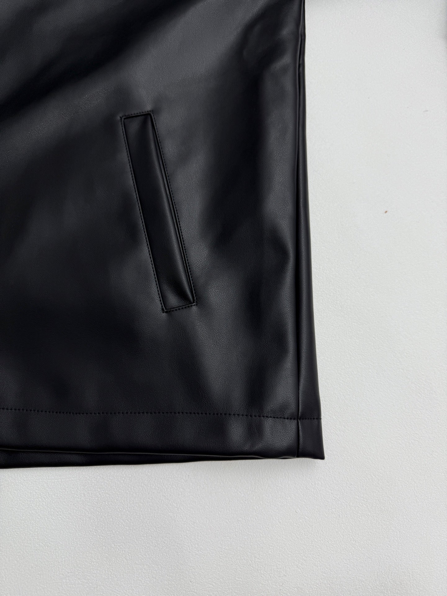 Black leather-look jacket sleeve cuff and side pocket with vertical stitch