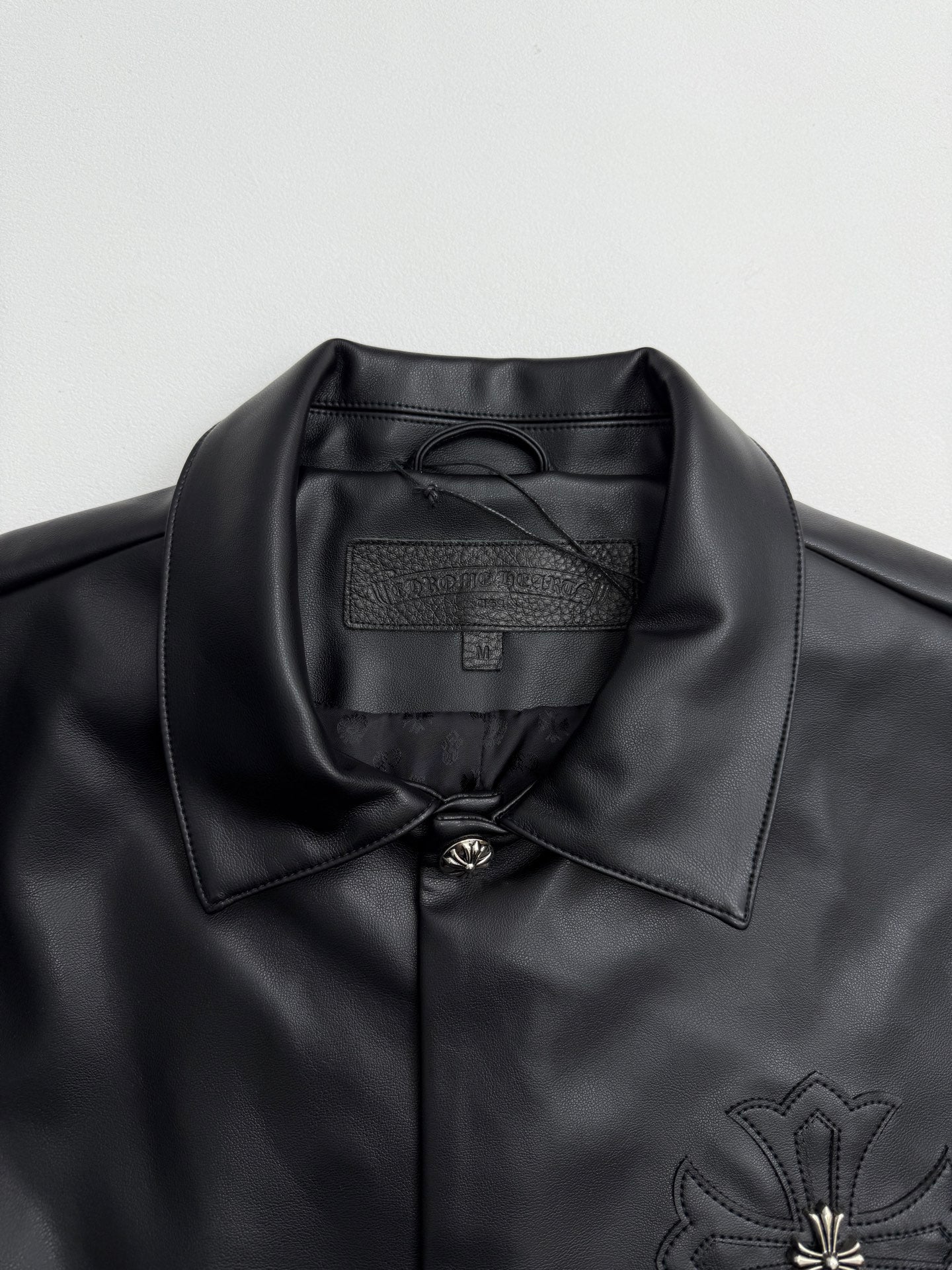 Black leather-look jacket collar with inner label and button placket