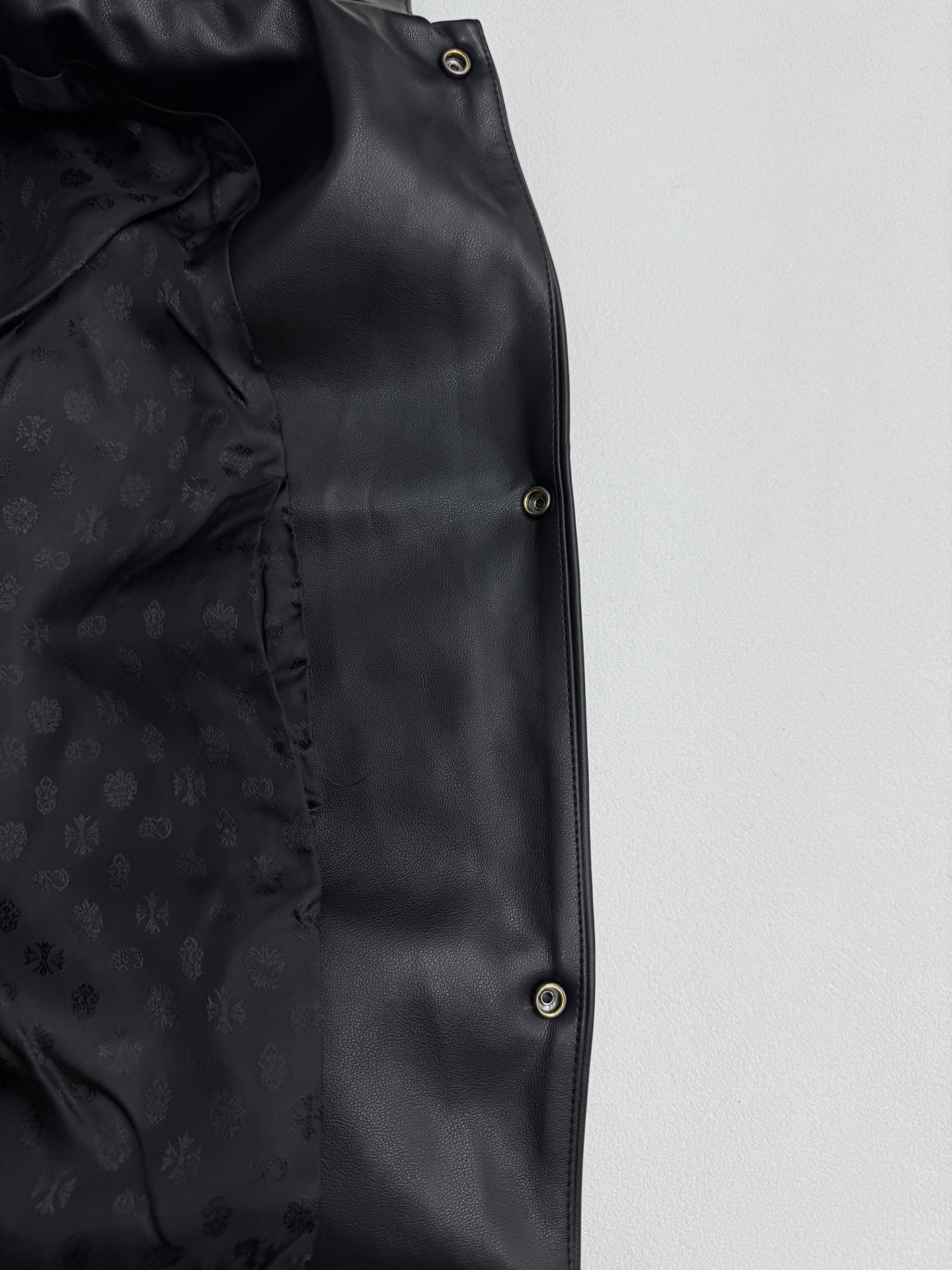 Black leather-look jacket front panel with dark snap buttons