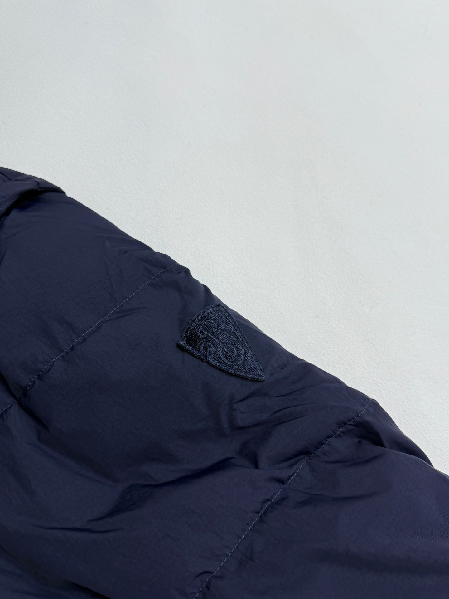 Navy puffer sleeve with stitched seam lines and small logo patch