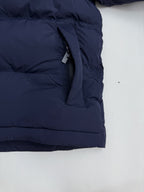 Navy puffer jacket lower front pocket with hanging fabric strap