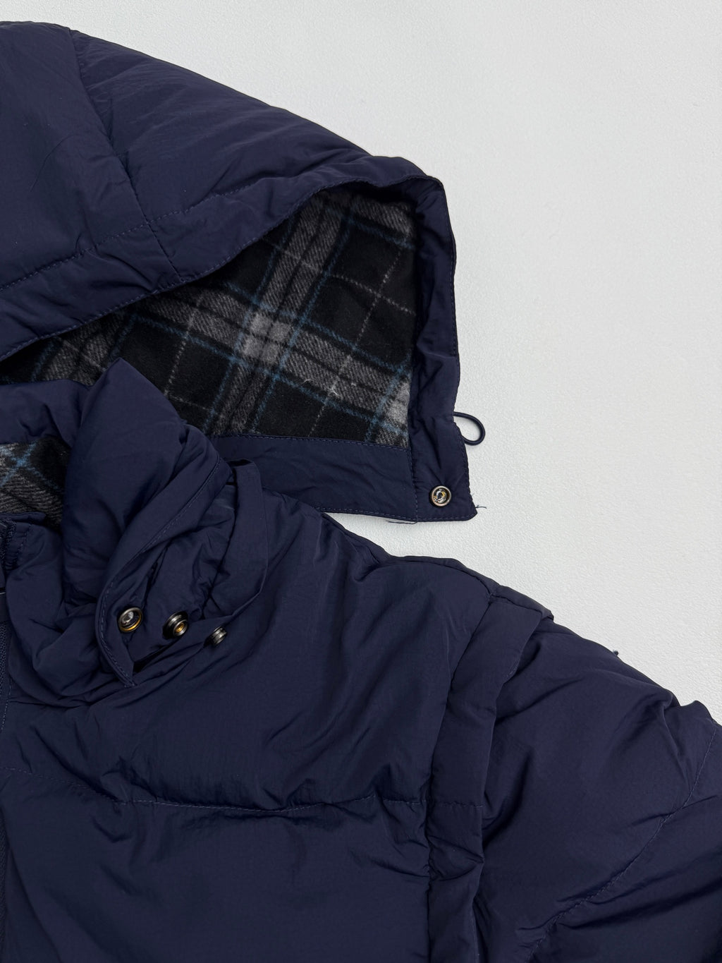 Navy puffer jacket with plaid-lined hood and snap-button cuff