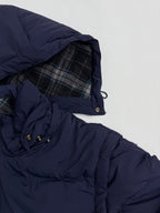Navy puffer jacket with plaid-lined hood and snap-button cuff