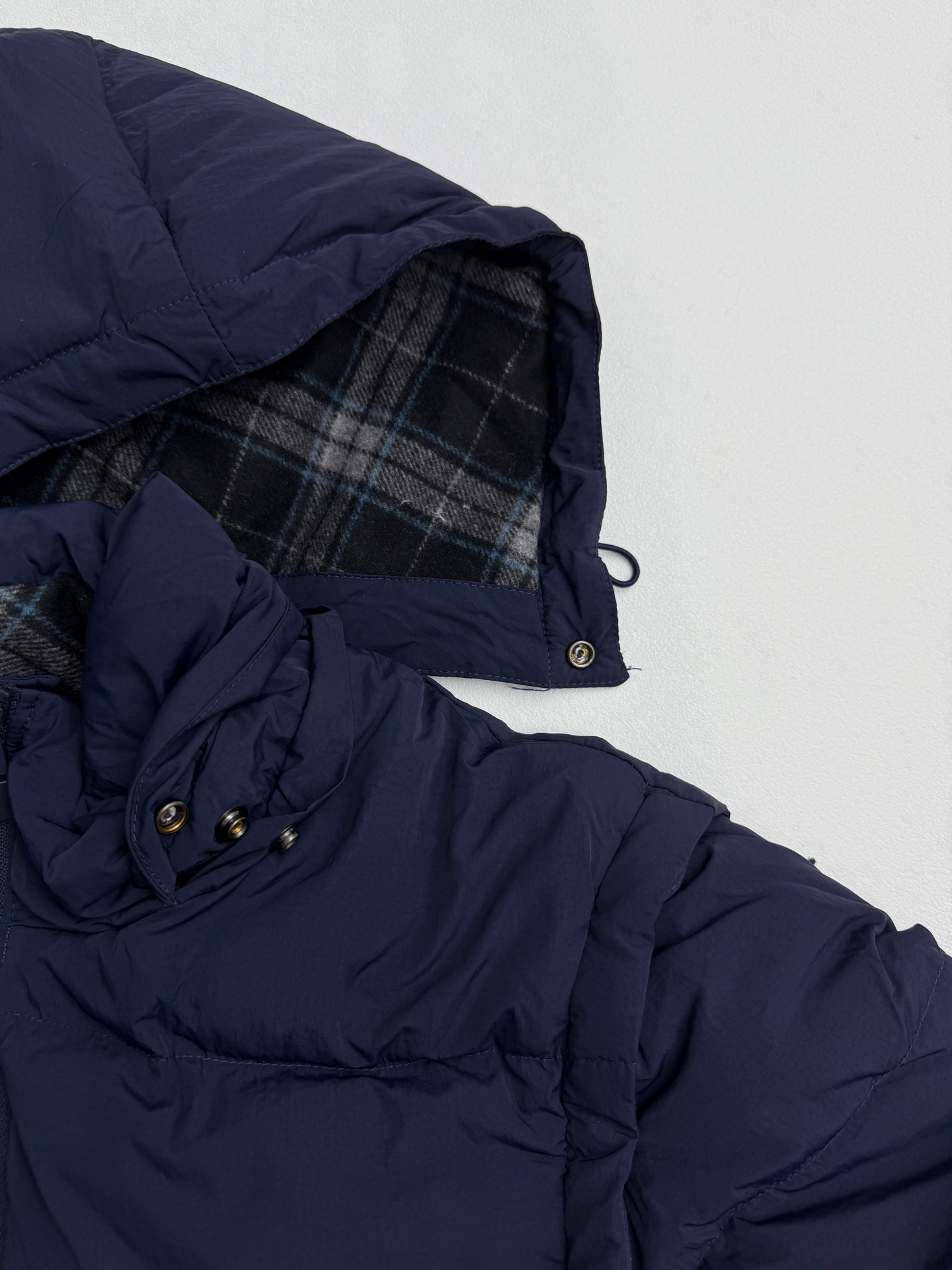 Navy puffer jacket with plaid-lined hood and snap-button cuff