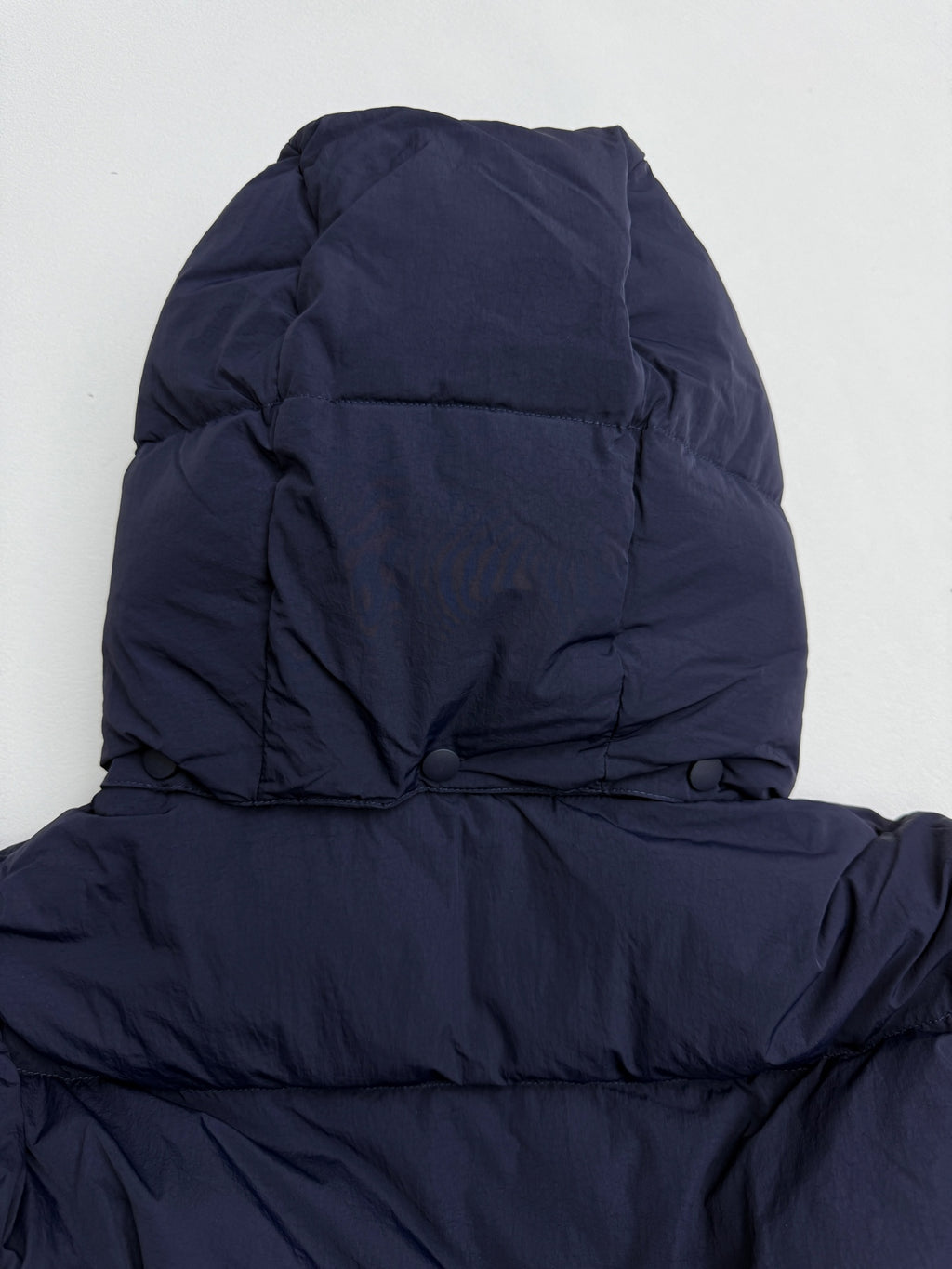 Navy hooded puffer jacket hood and upper back view with padded seams
