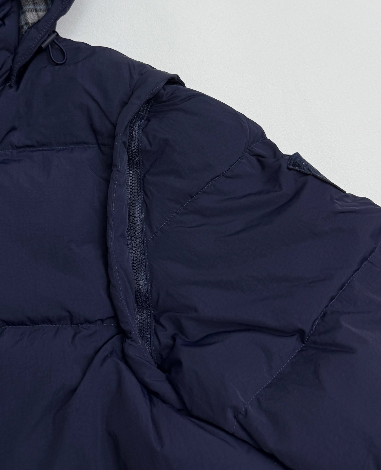 Navy quilted puffer jacket close-up of zipper and padded shoulder seam