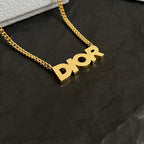 Close-up of gold-tone Dior pendant on curb chain necklace.