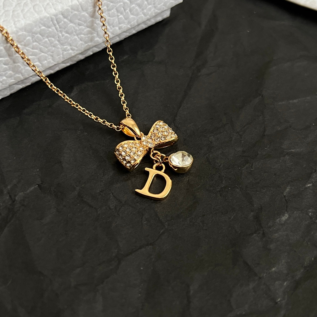 Gold-tone pendant necklace with layered charms and letter D pendant