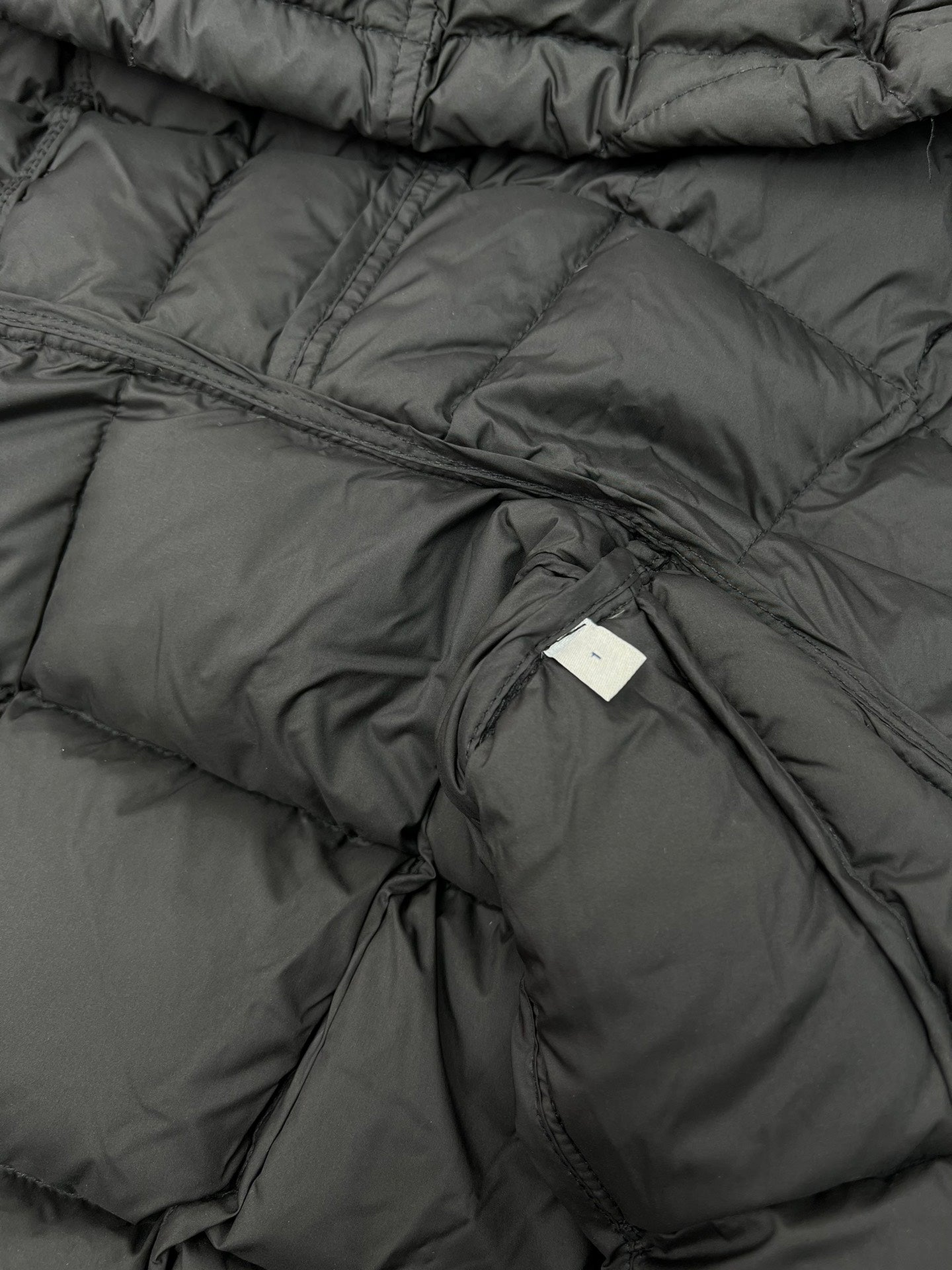 Inside lining and stitching on black puffer coat with label tab