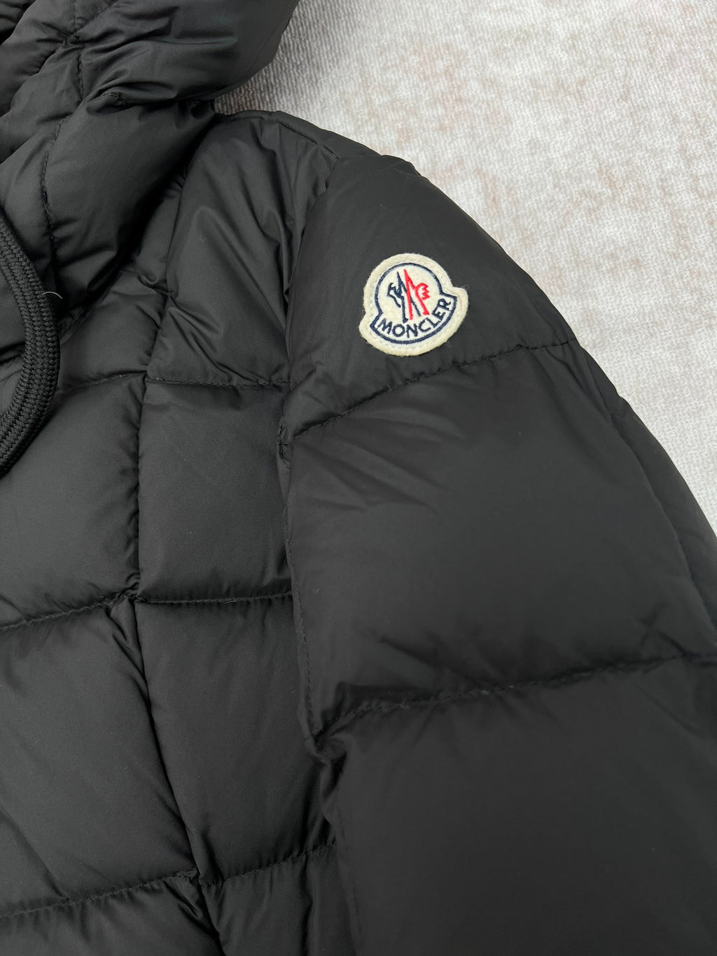 Moncler logo patch on black puffer coat shoulder