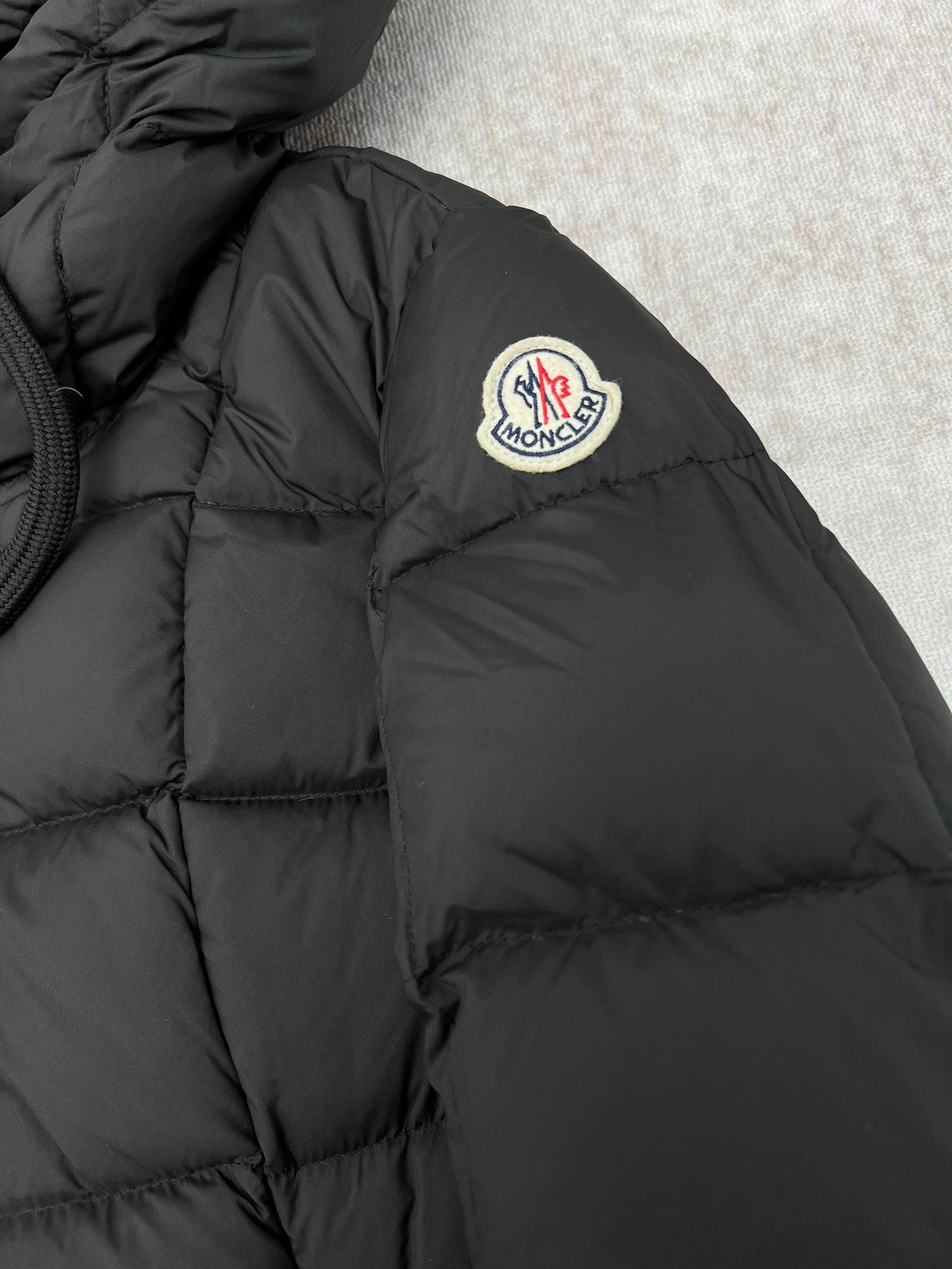 Moncler logo patch on black puffer coat shoulder