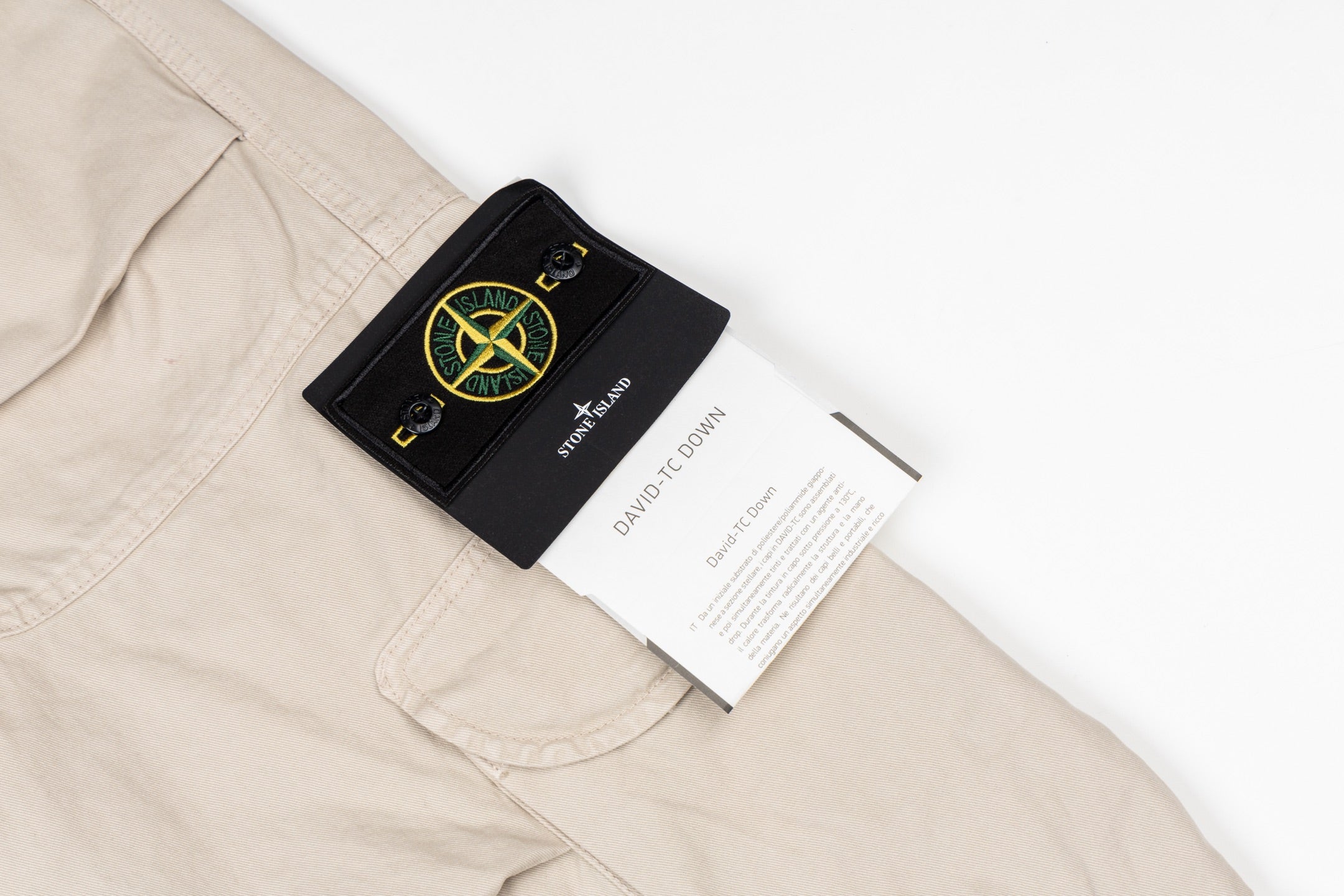 Stone Island cargo pants with black brand patch and white care label on pocket
