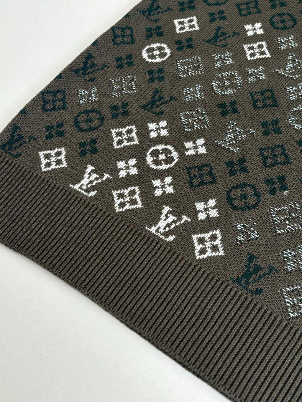 Close-up of dark knit sweater fabric with white and teal logo-style pattern