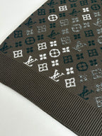 Close-up of dark knit sweater fabric with white and teal logo-style pattern