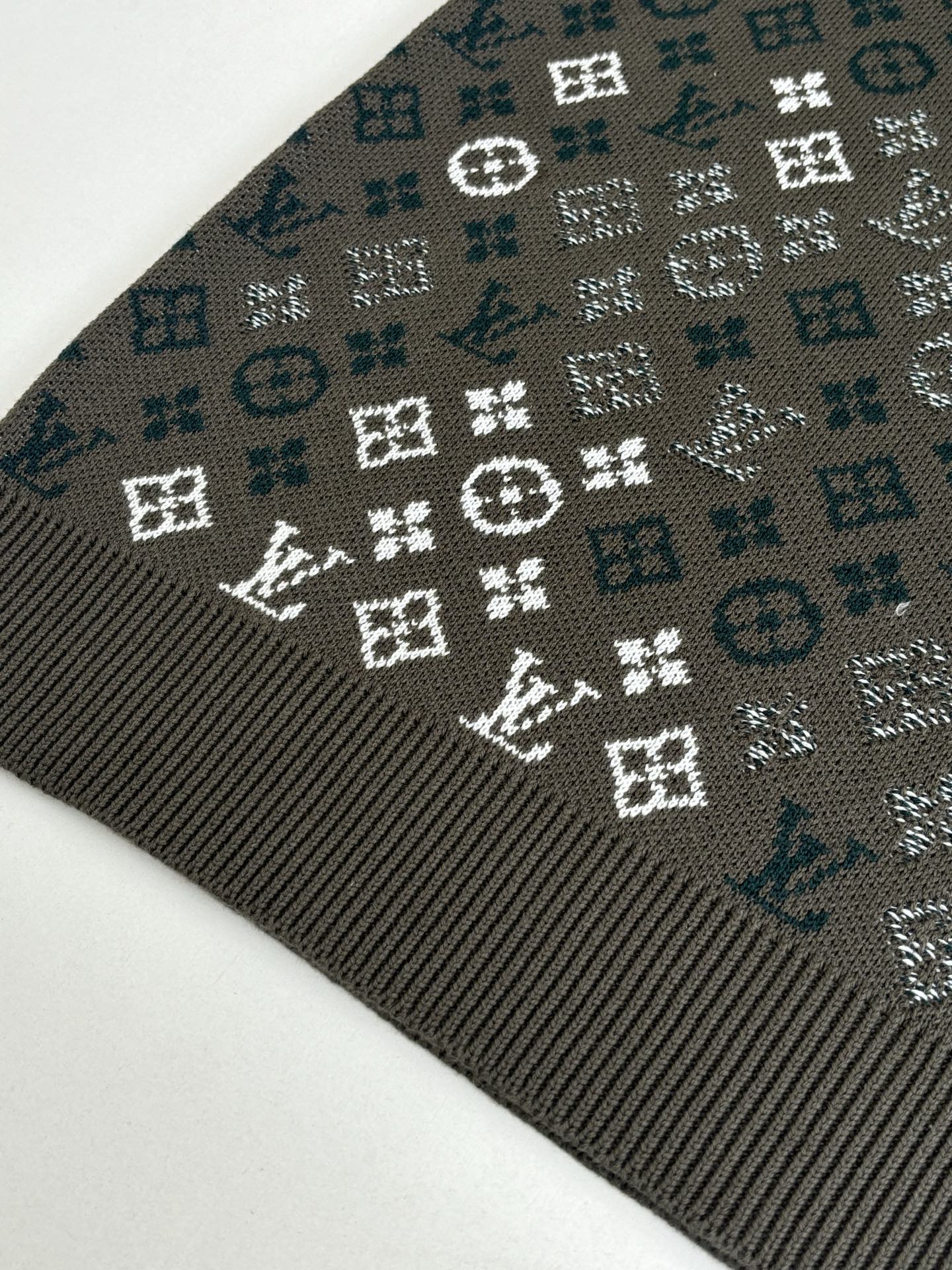 Close-up of dark knit sweater fabric with white and teal logo-style pattern