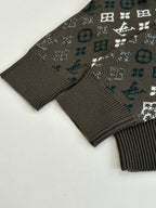 Knit sweater cuff and hem detail in dark tone with allover logo-style pattern