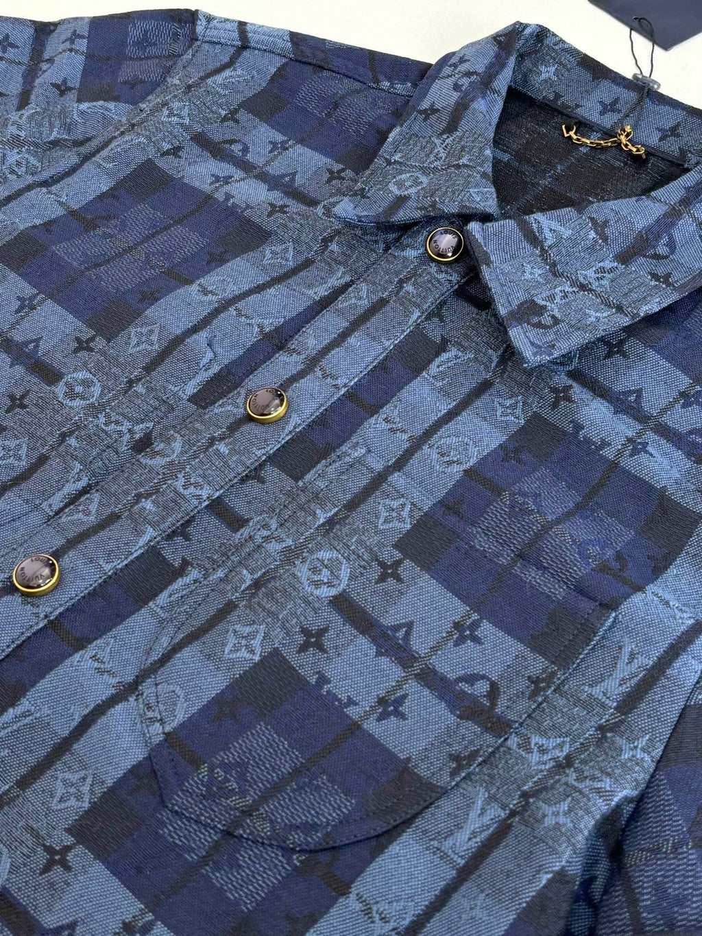 Louis Vuitton blue plaid jacket close-up with monogram pattern and round gold buttons
