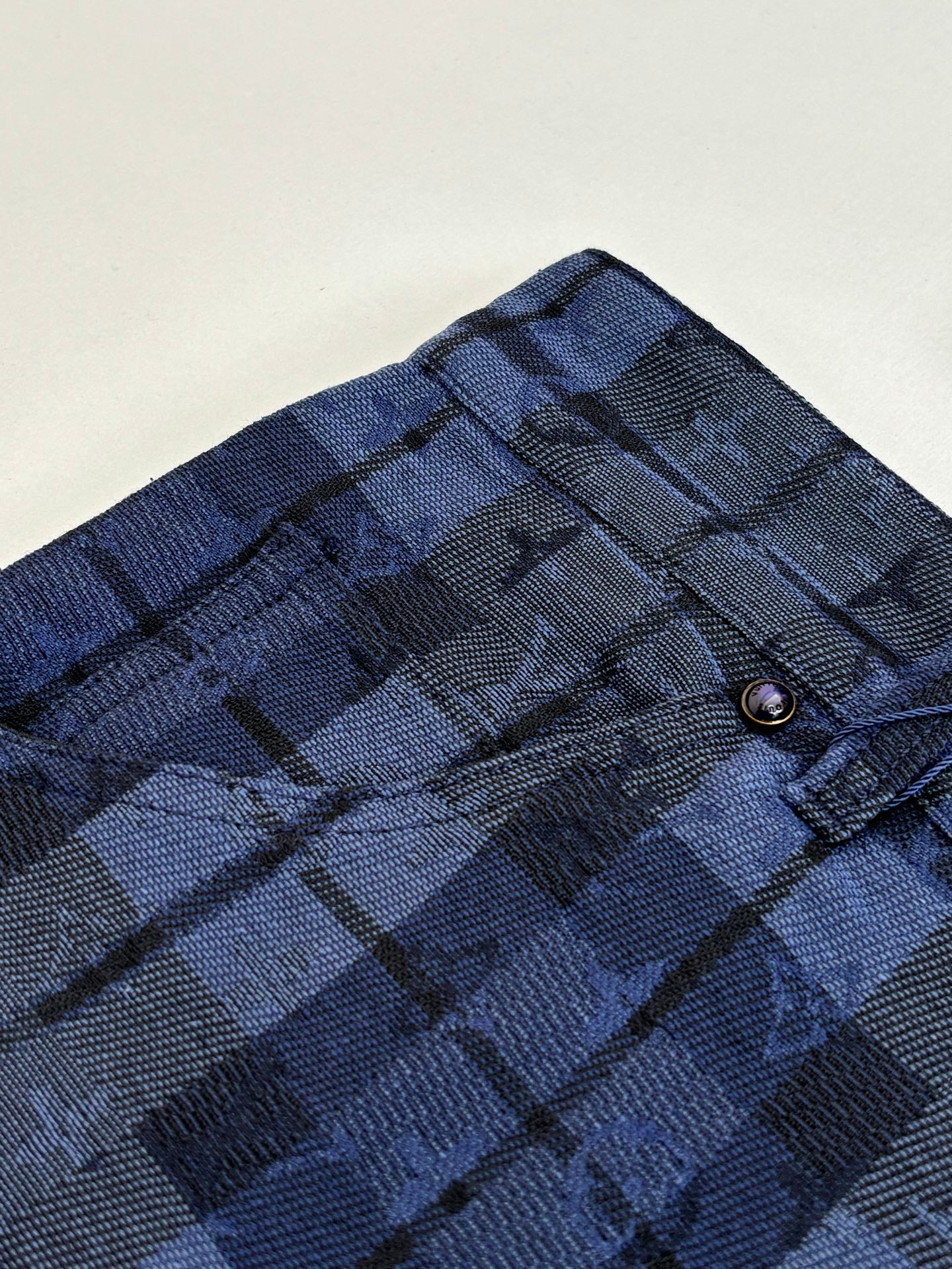 Dark blue plaid fabric with stitched waistband and belt loops detail