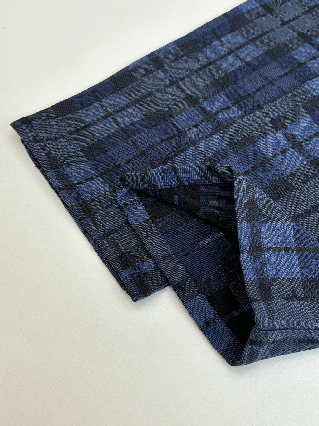 Blue plaid trousers leg with stitched pocket and folded cuff detail