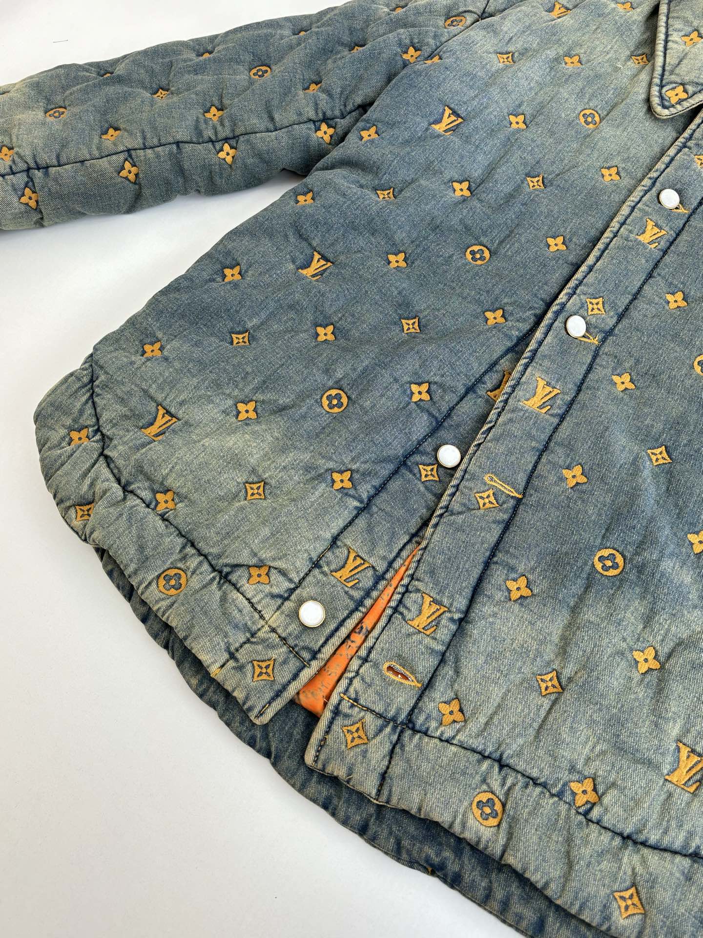Louis Vuitton denim jacket front close-up with orange-ink monogram pattern and snaps