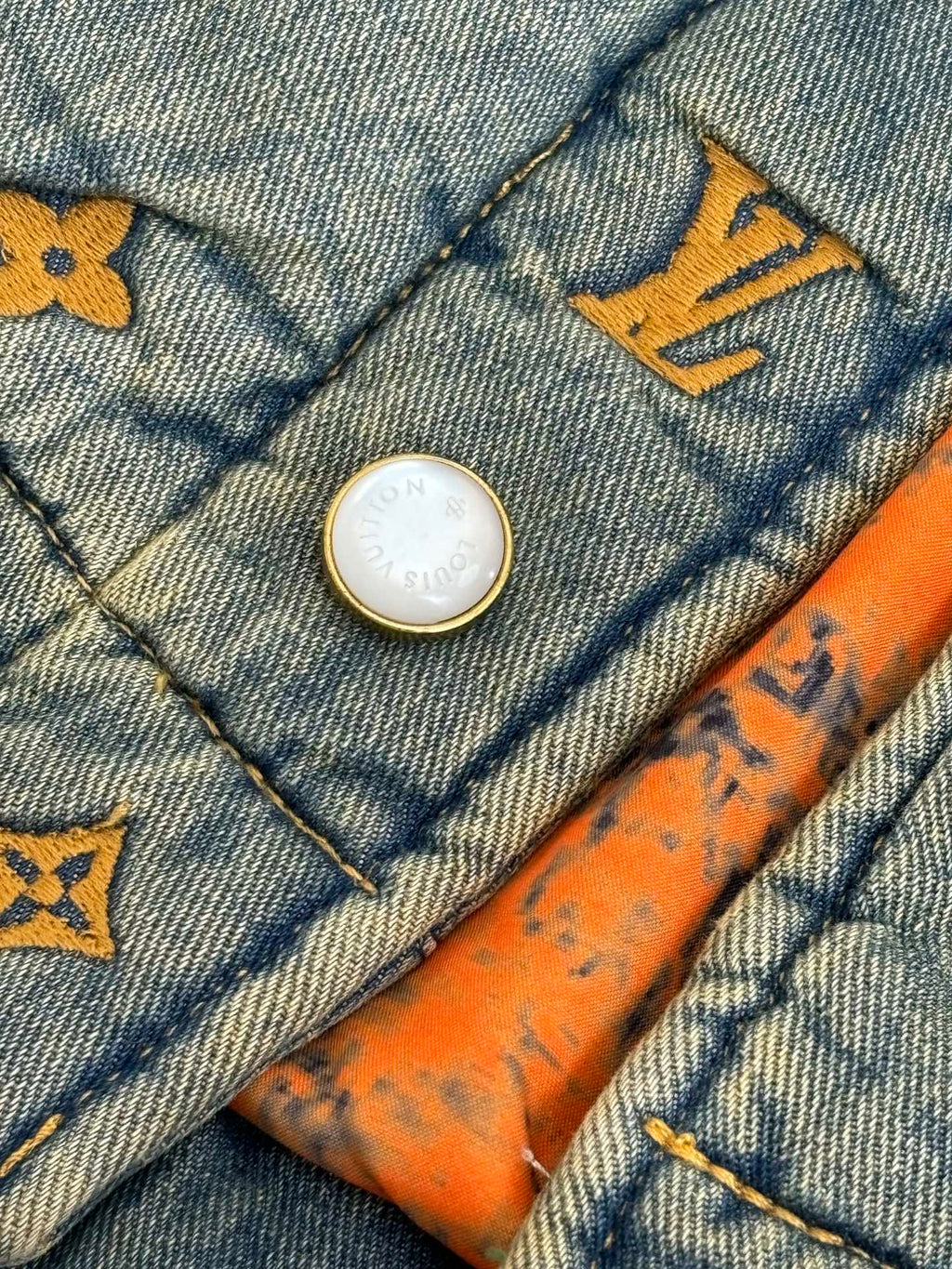 Louis Vuitton denim jacket button detail with yellow monogram trim and orange stitching