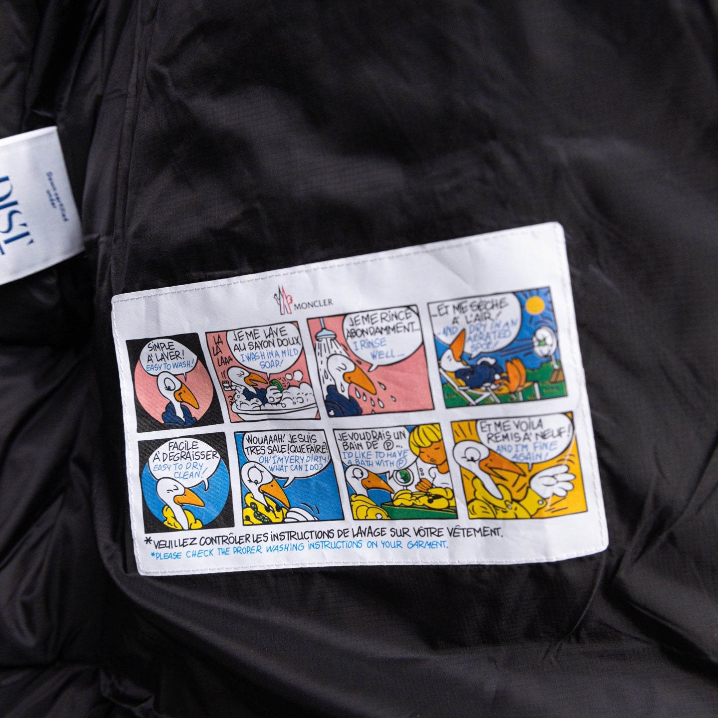 Long black puffer jacket, colorful care instructions label on front