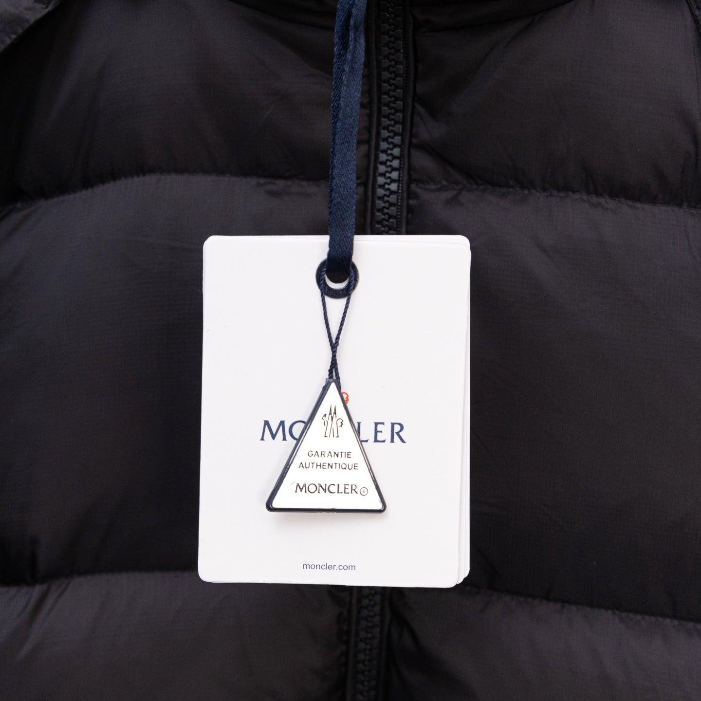 Moncler authenticity hang tag on black puffer jacket