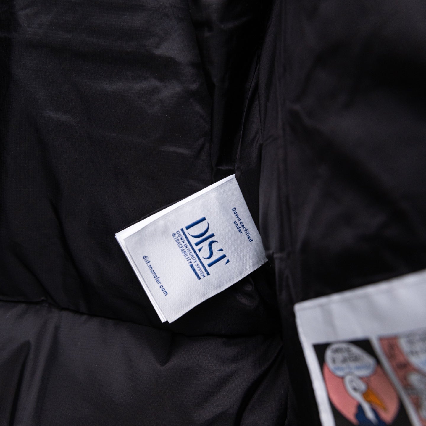 Long black puffer jacket, white care labels on inner panel