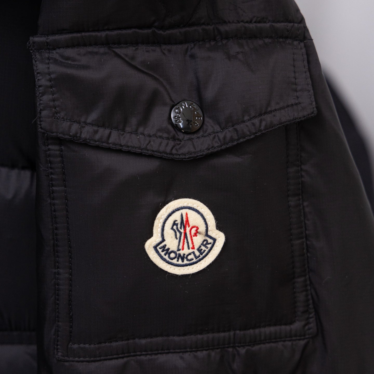 Moncler logo patch on black long puffer jacket chest