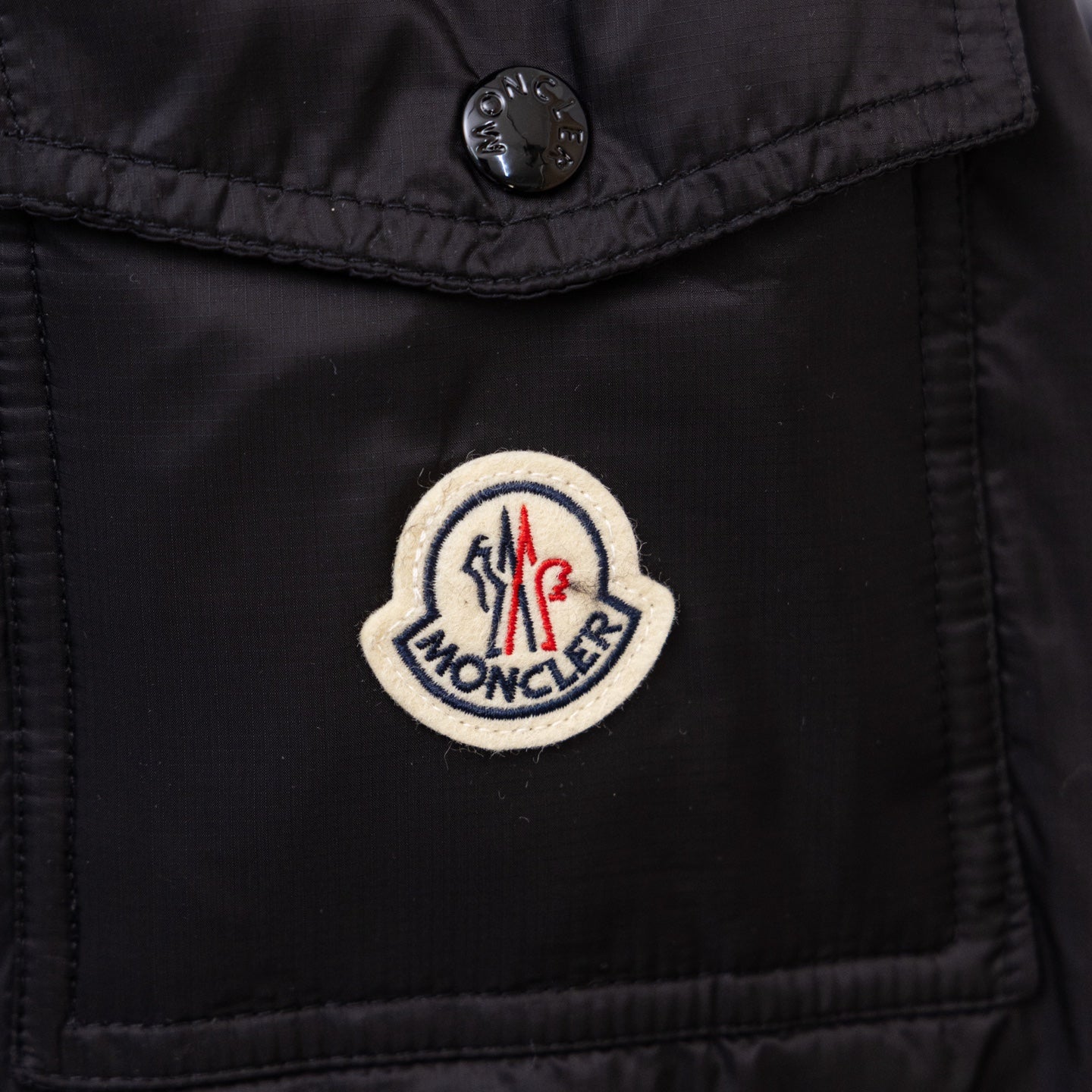 Moncler logo patch on black long puffer jacket chest