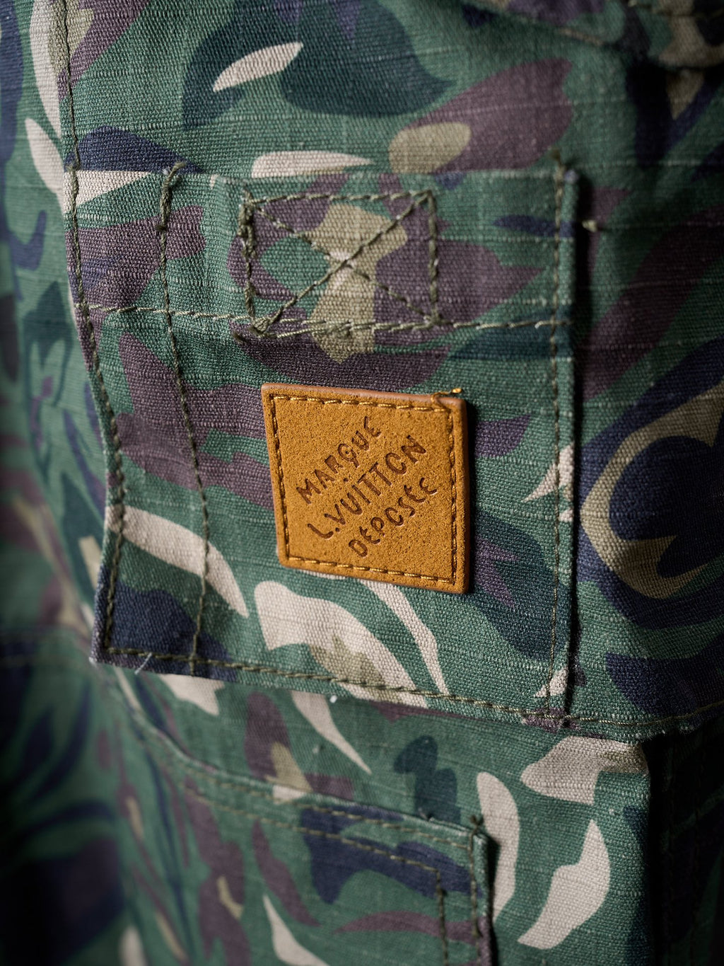 Louis Vuitton camouflage pants close-up of leather brand patch on front pocket