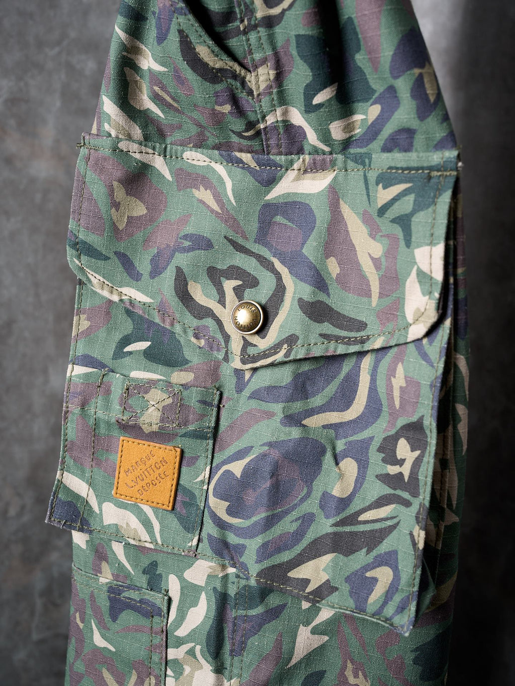 Louis Vuitton camouflage cargo pants side close-up of flap pocket and metal button