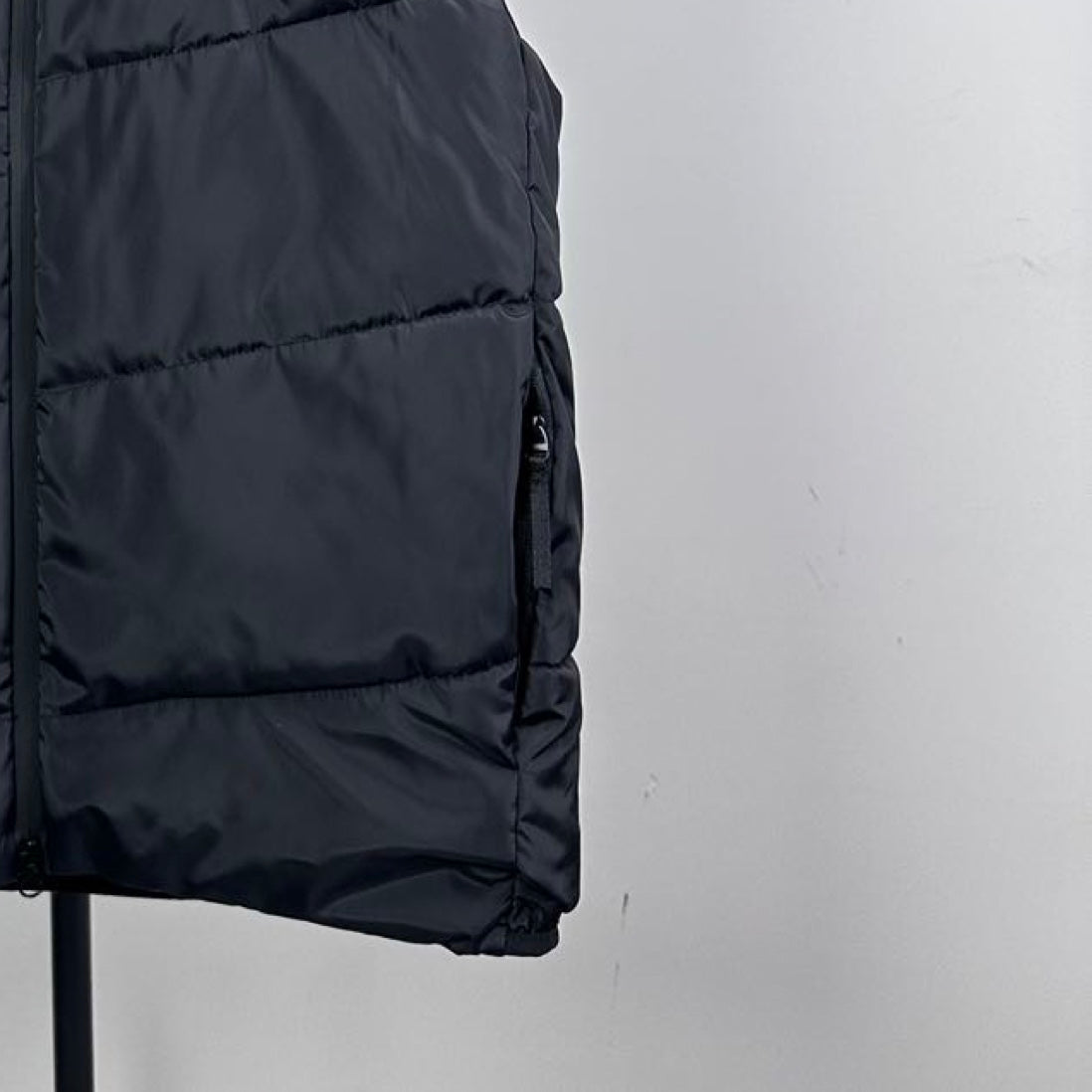 Moncler hooded puffer vest, close-up of dark quilted fabric and curved hem