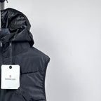 Moncler hooded puffer vest shoulder and white logo hang tag on dark fabric