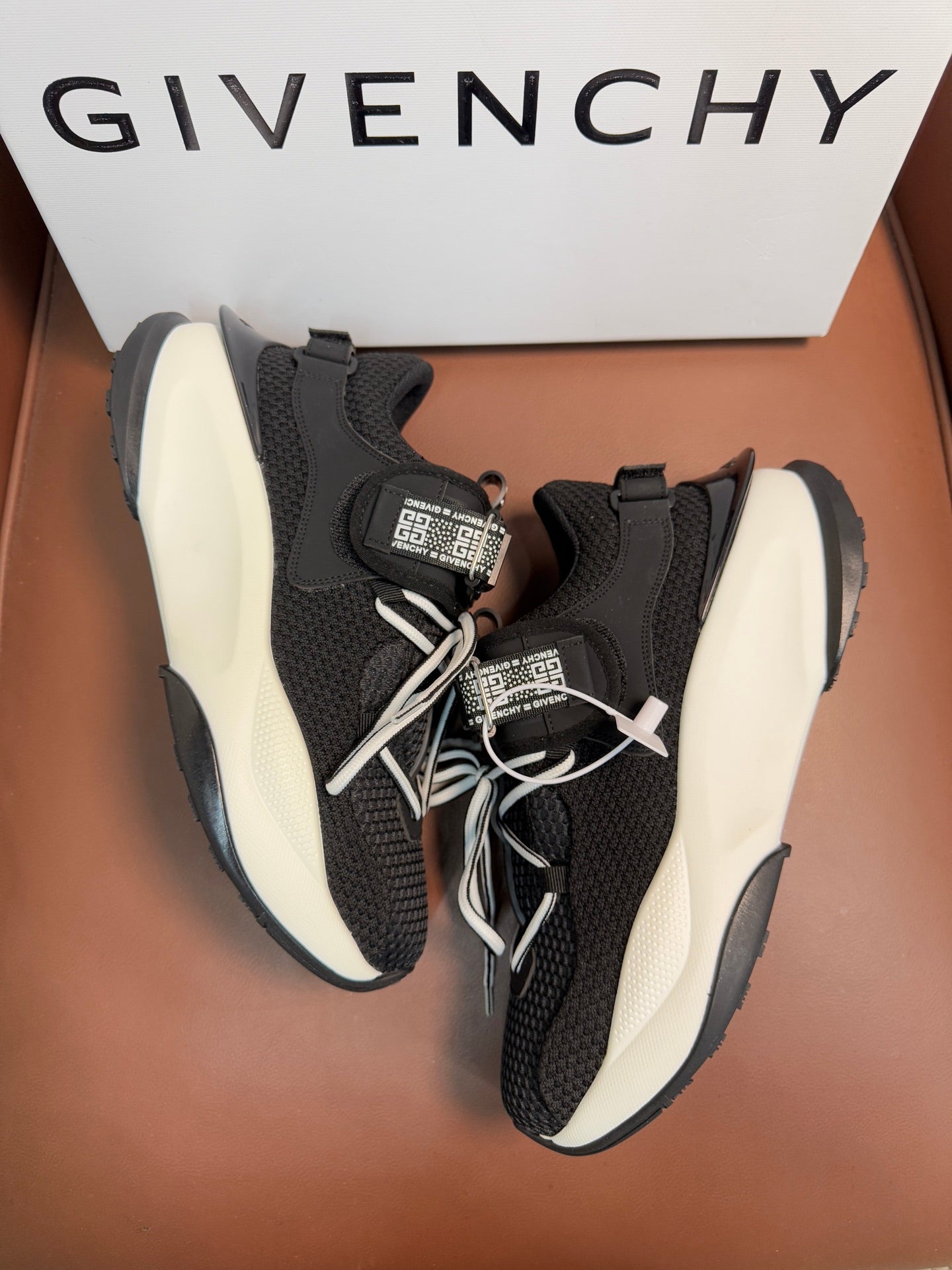 Luxury black knit sneakers with white soles, laces, and hook-and-loop logo strap