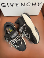 Luxury black sneakers with white sole, lace-up ties, and side logo strap