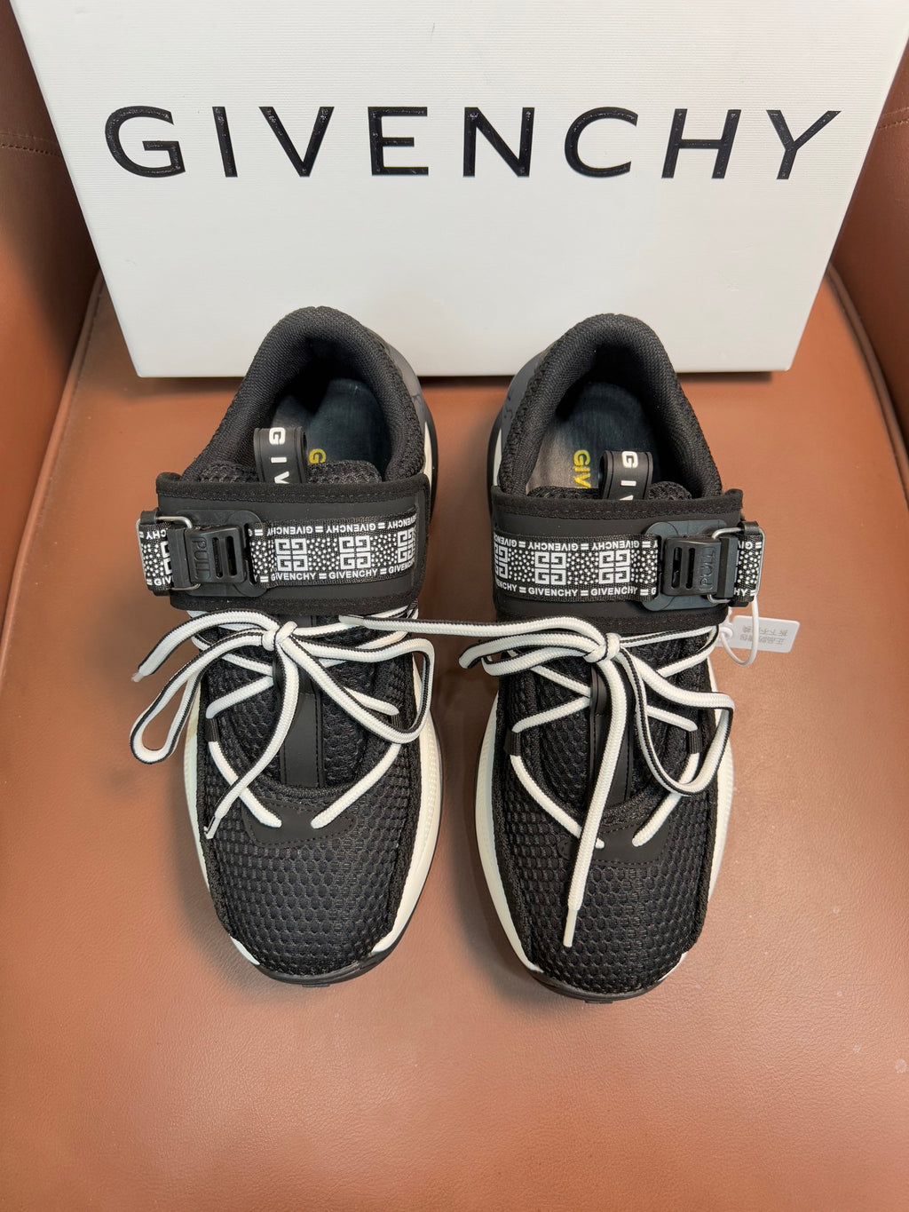Luxury black knit sneakers with white soles, lace-up front, and logo strap details