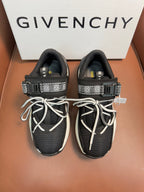 Luxury black knit sneakers with white soles, lace-up front, and logo strap details