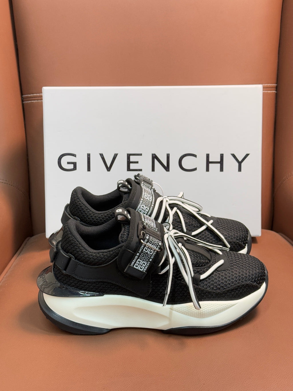 Luxury black sneakers with white soles, lace-up front, and tall strap with logo panel