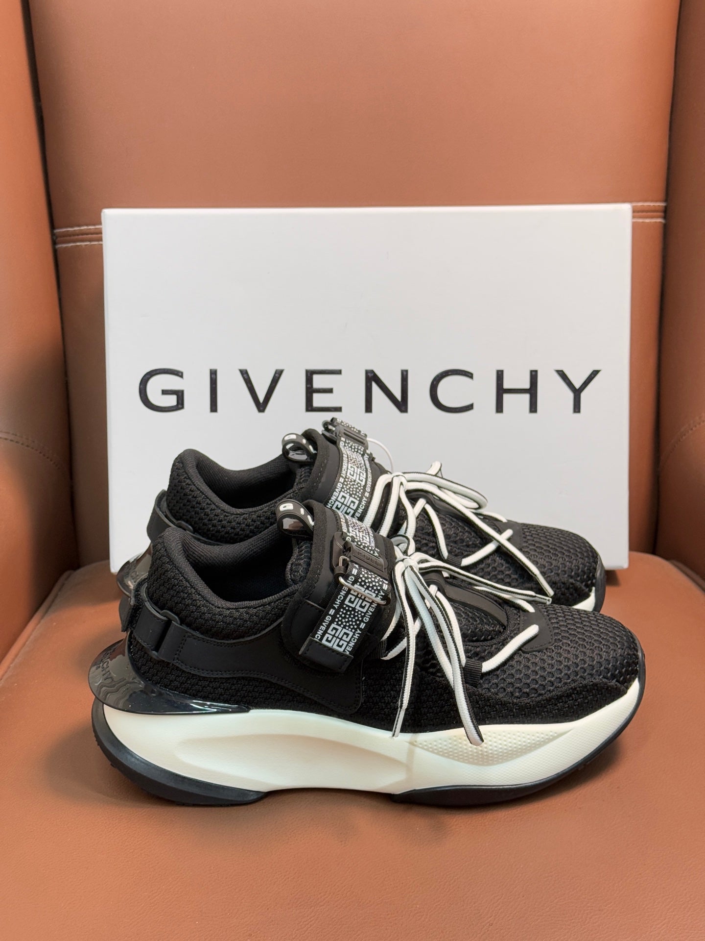 Luxury black sneakers with white soles, lace-up front, and tall strap with logo panel