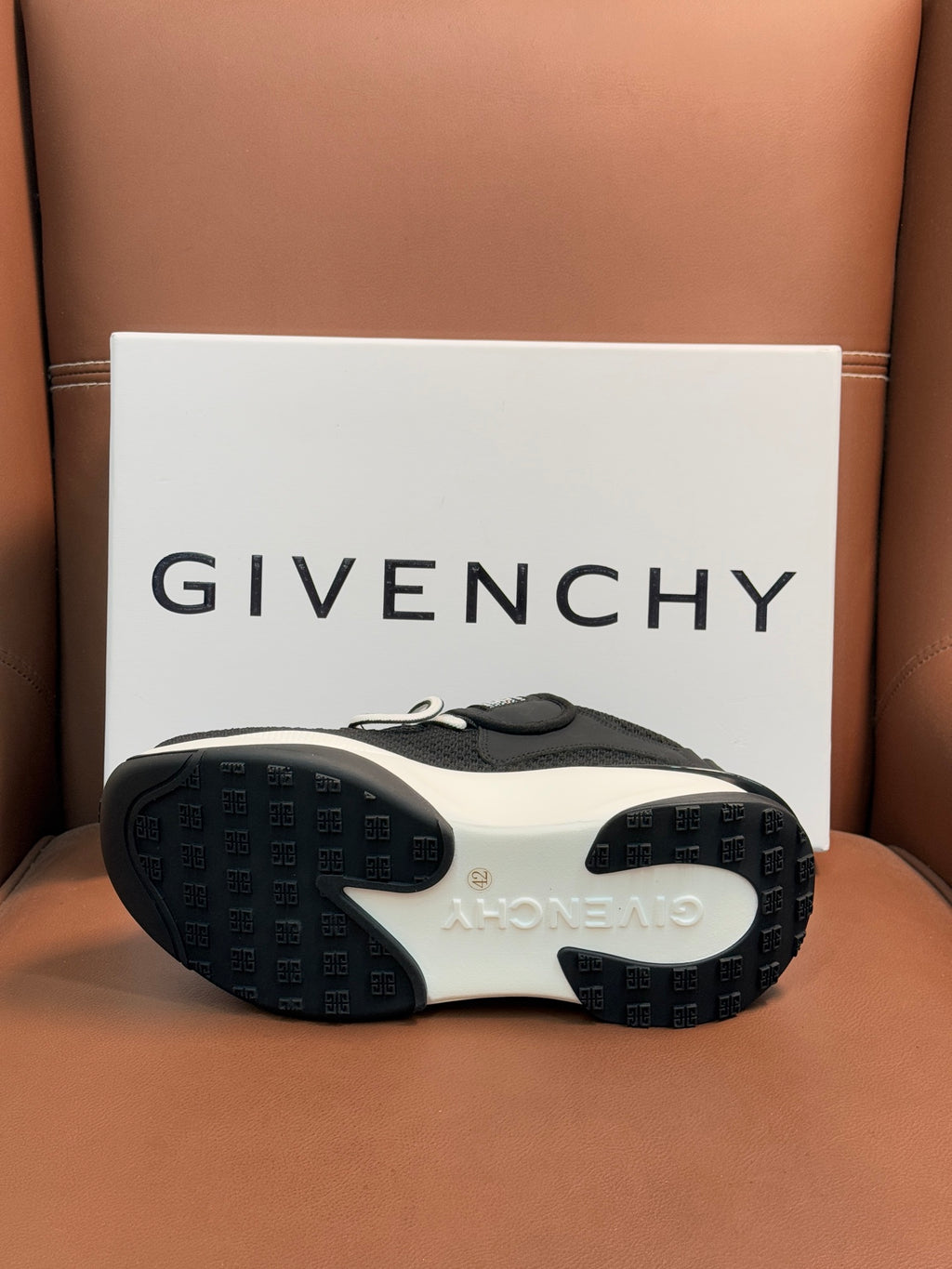 Luxury black sneakers outsole view with textured rubber sole and light trim