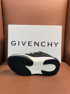 Luxury black sneakers outsole view with textured rubber sole and light trim