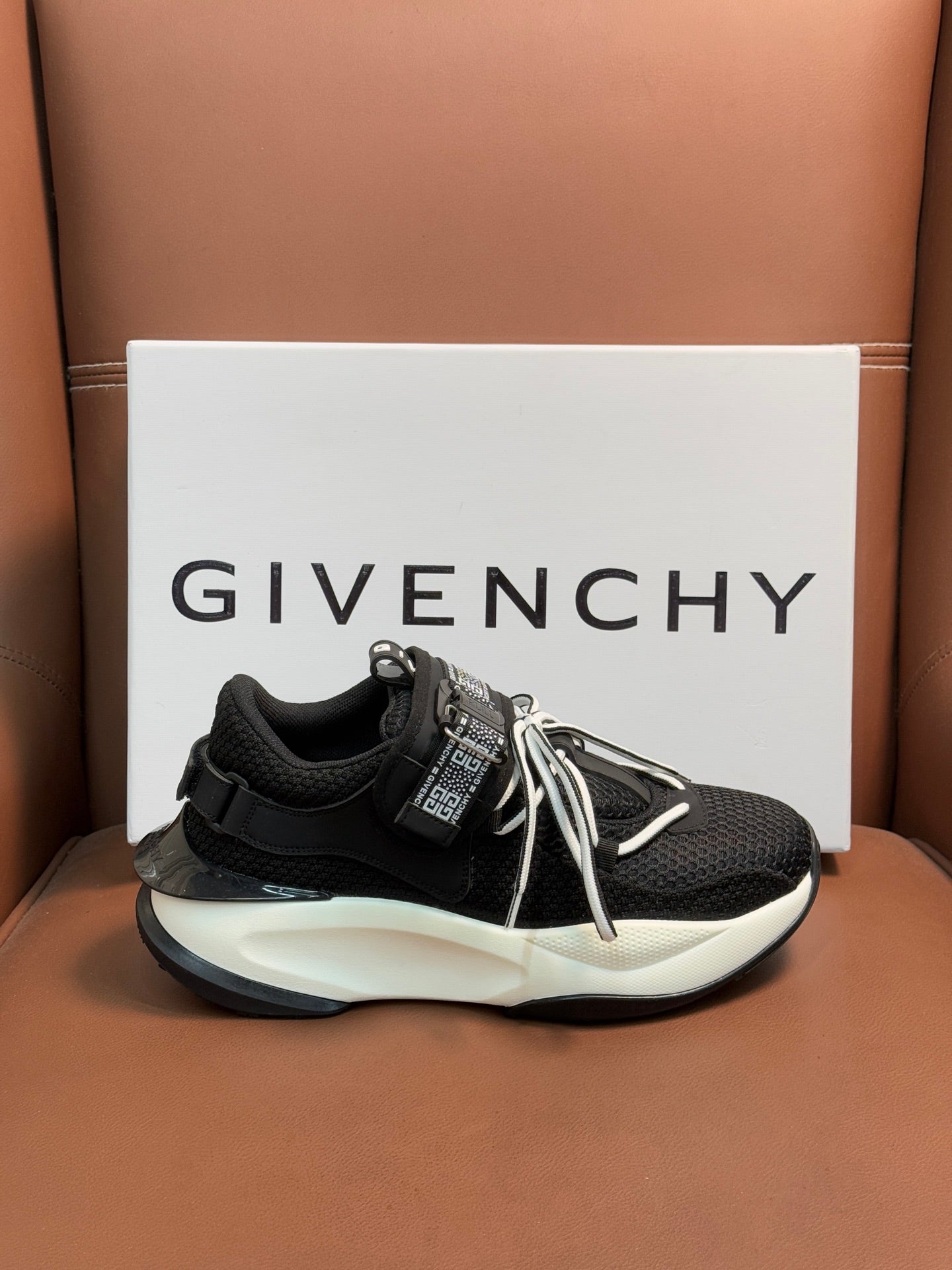 Luxury black sneakers with white soles, lace-up ties, and logo strap detail