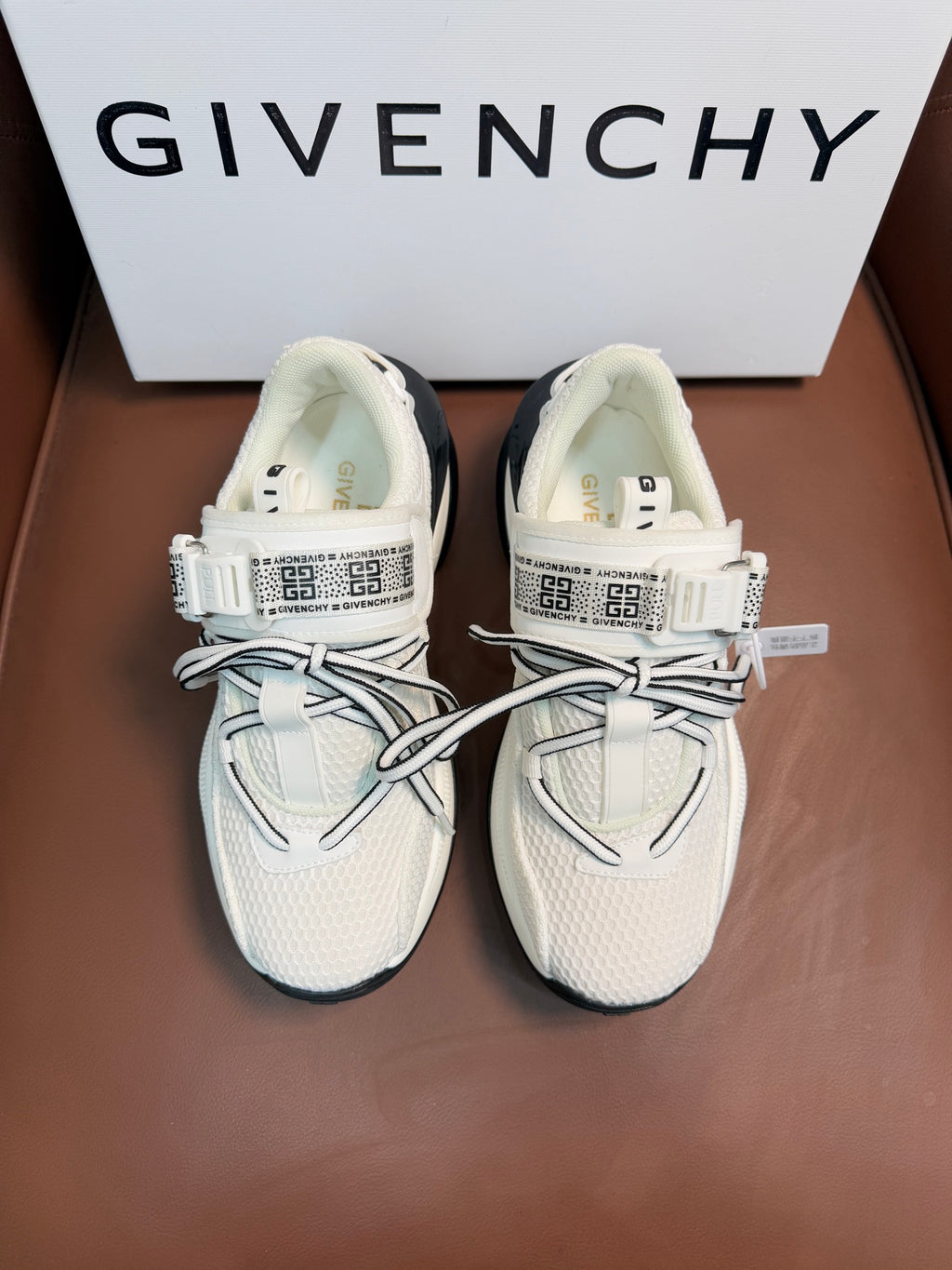 White leather-look sneakers with gray laces, side strap with repeating logo on tongue