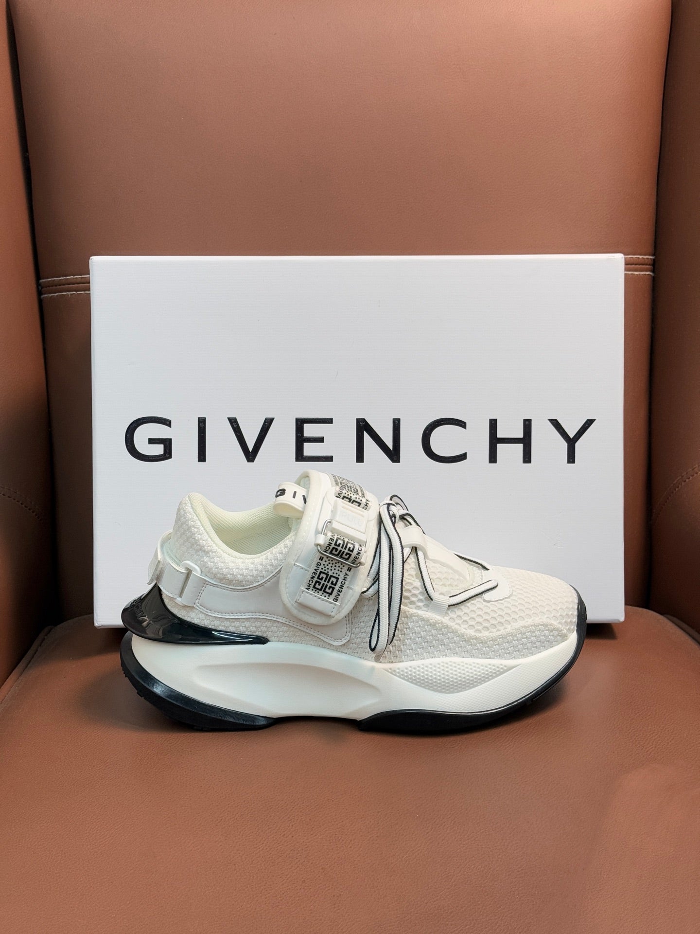 White sneakers with logo strap, gray laces, and thick dark outsole edge