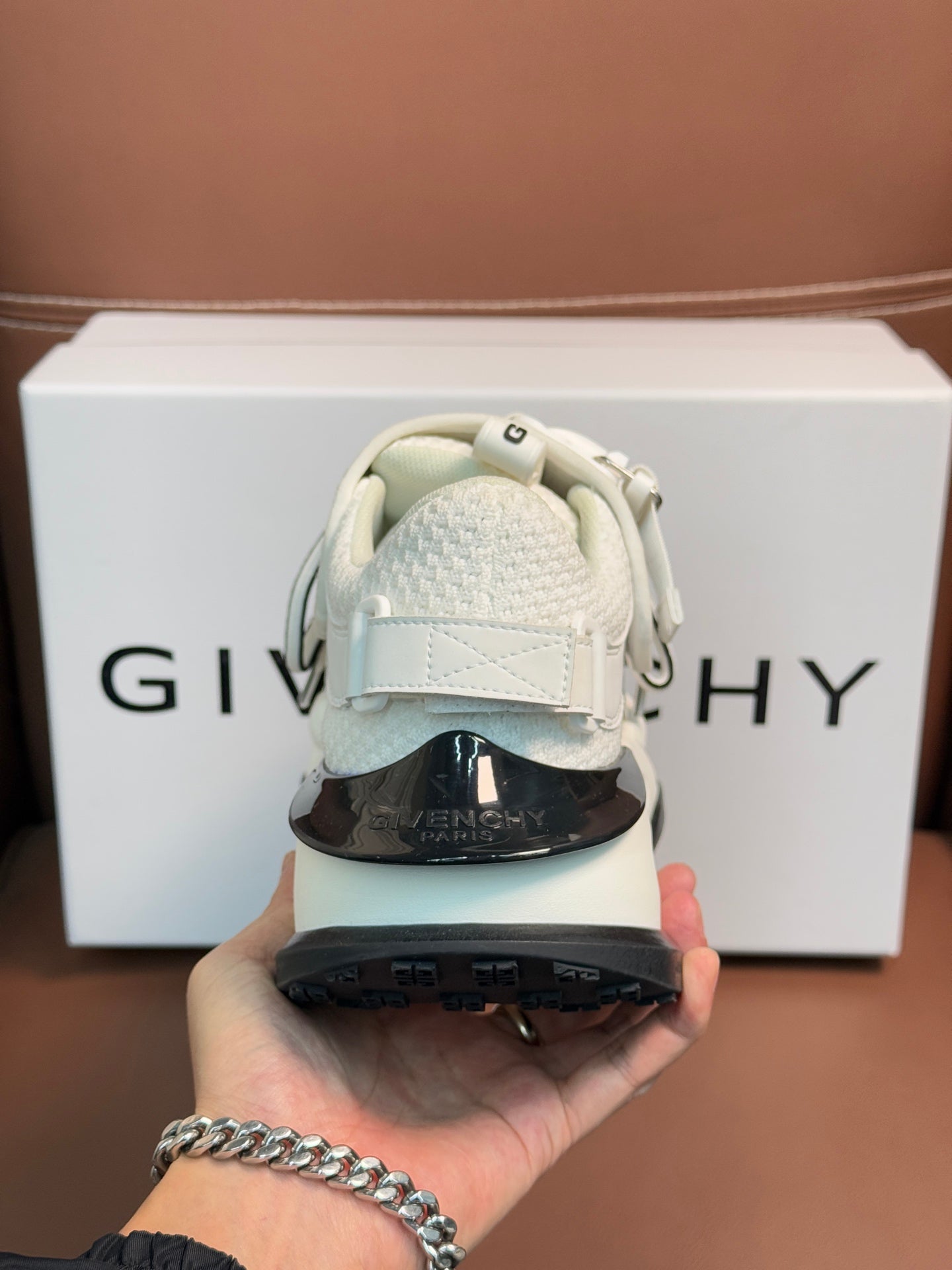 White sneakers heel close-up with dark outsole and embossed side logos