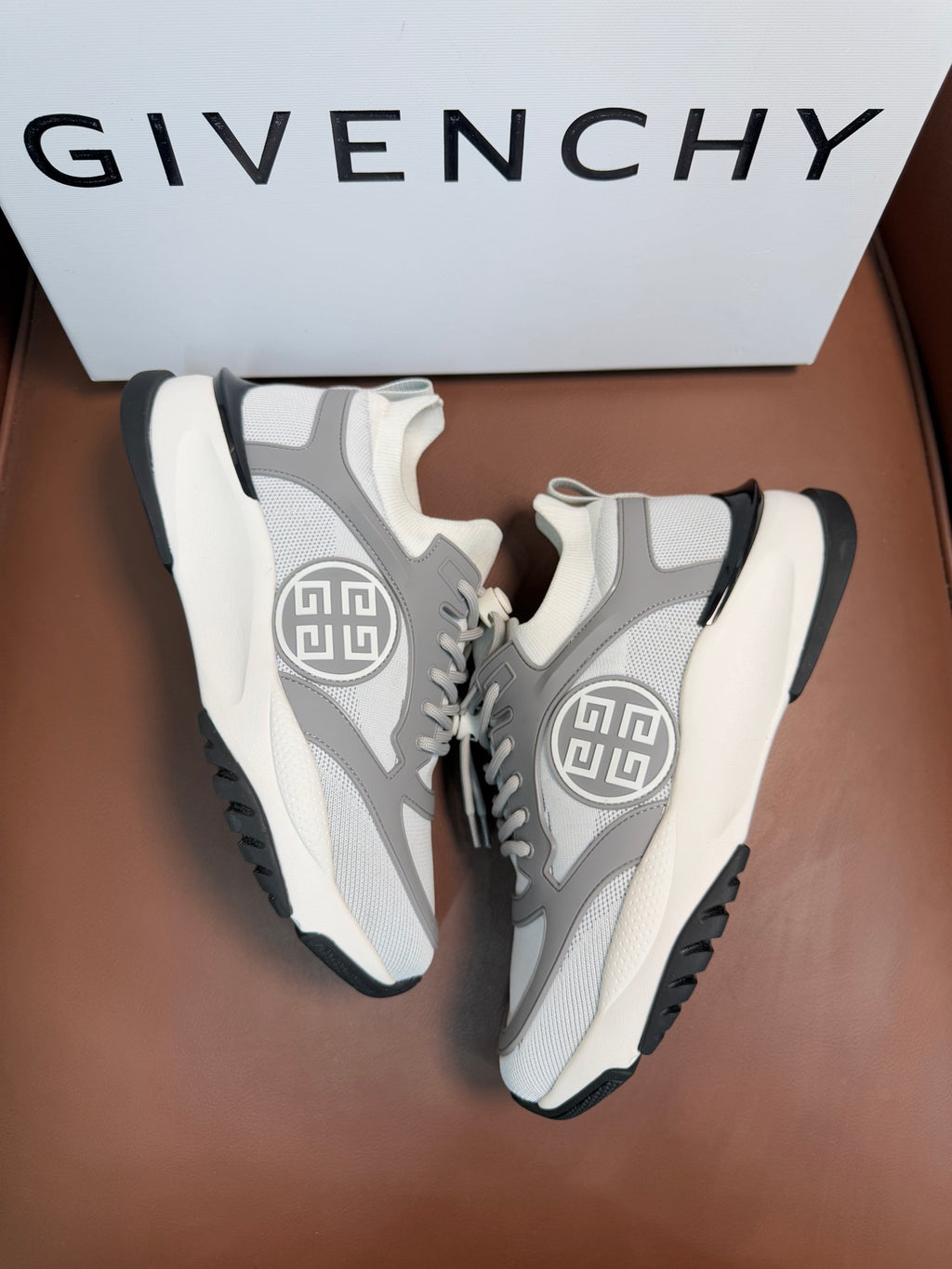 Light gray and white high-profile sneakers with textured mesh and side logo.