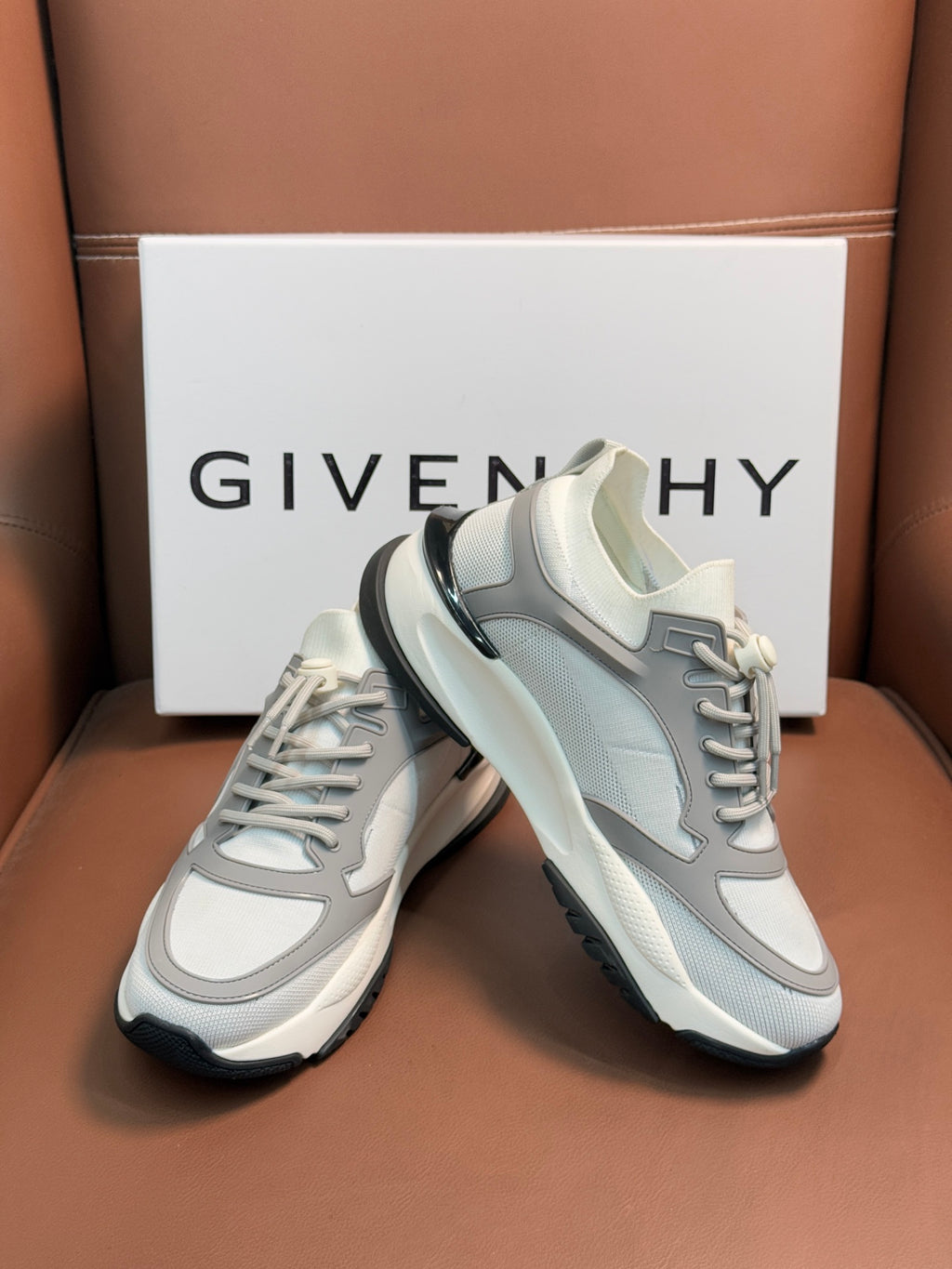 Light gray and white lace-up sneakers with rounded toe and layered sole.
