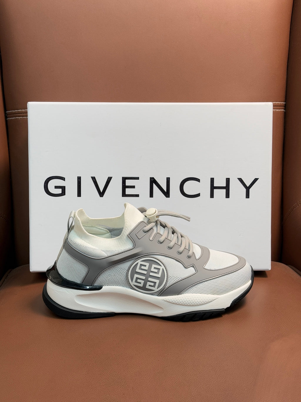 Light gray chunky sneakers with lace-up front and oval side logo patch.